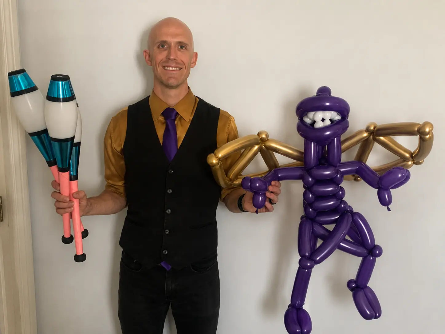 Dan holding juggling clubs beside a large purple balloon creation
