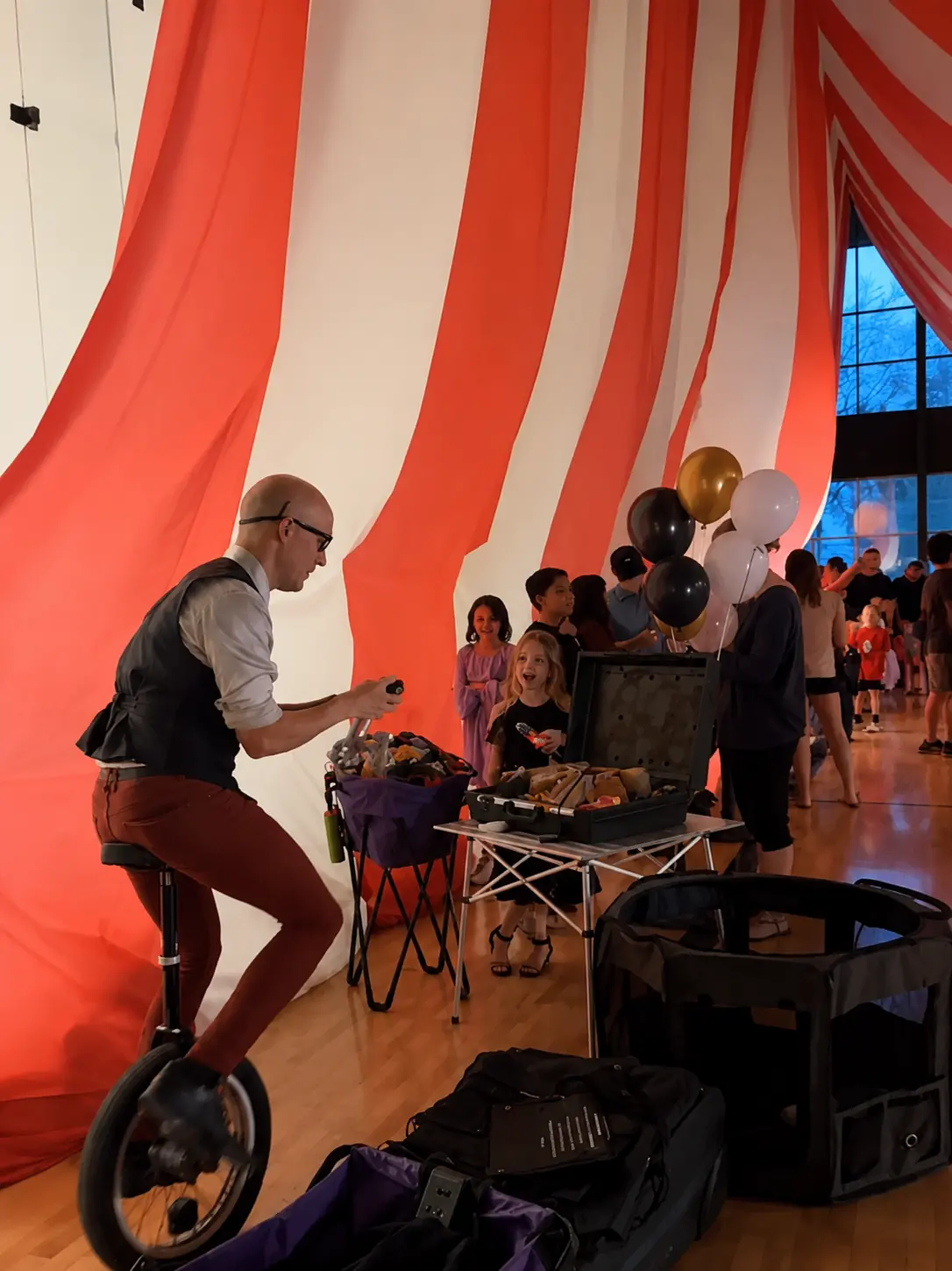 Dan twisting balloons for children while balancing on a unicycle