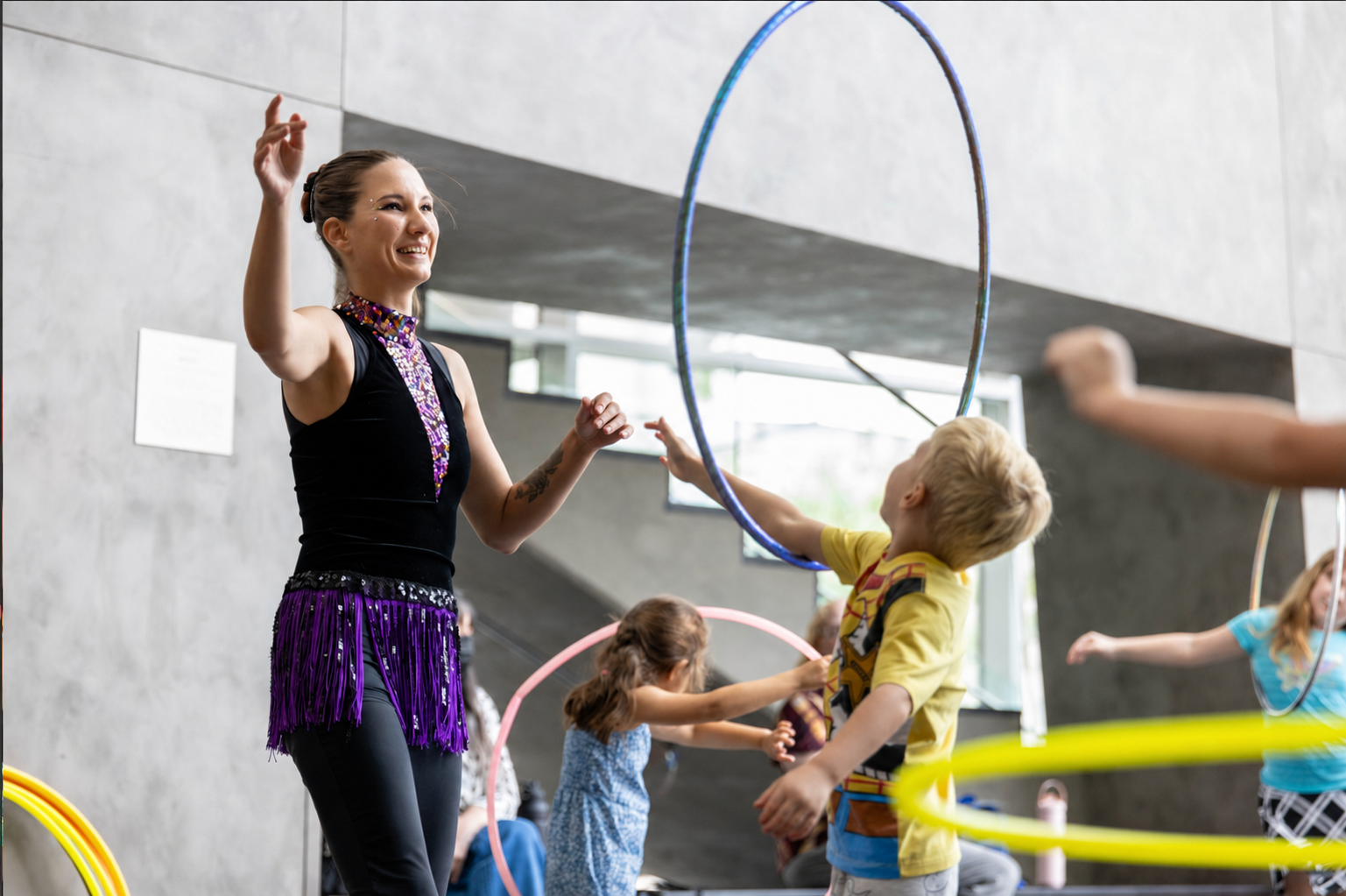Tabitha guiding children through hands-on hula hoop activities at a circus arts workshop